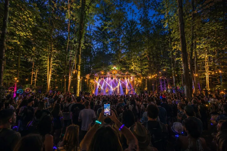 Nova Stage — open-air stage glowing at dusk with a dancing crowd